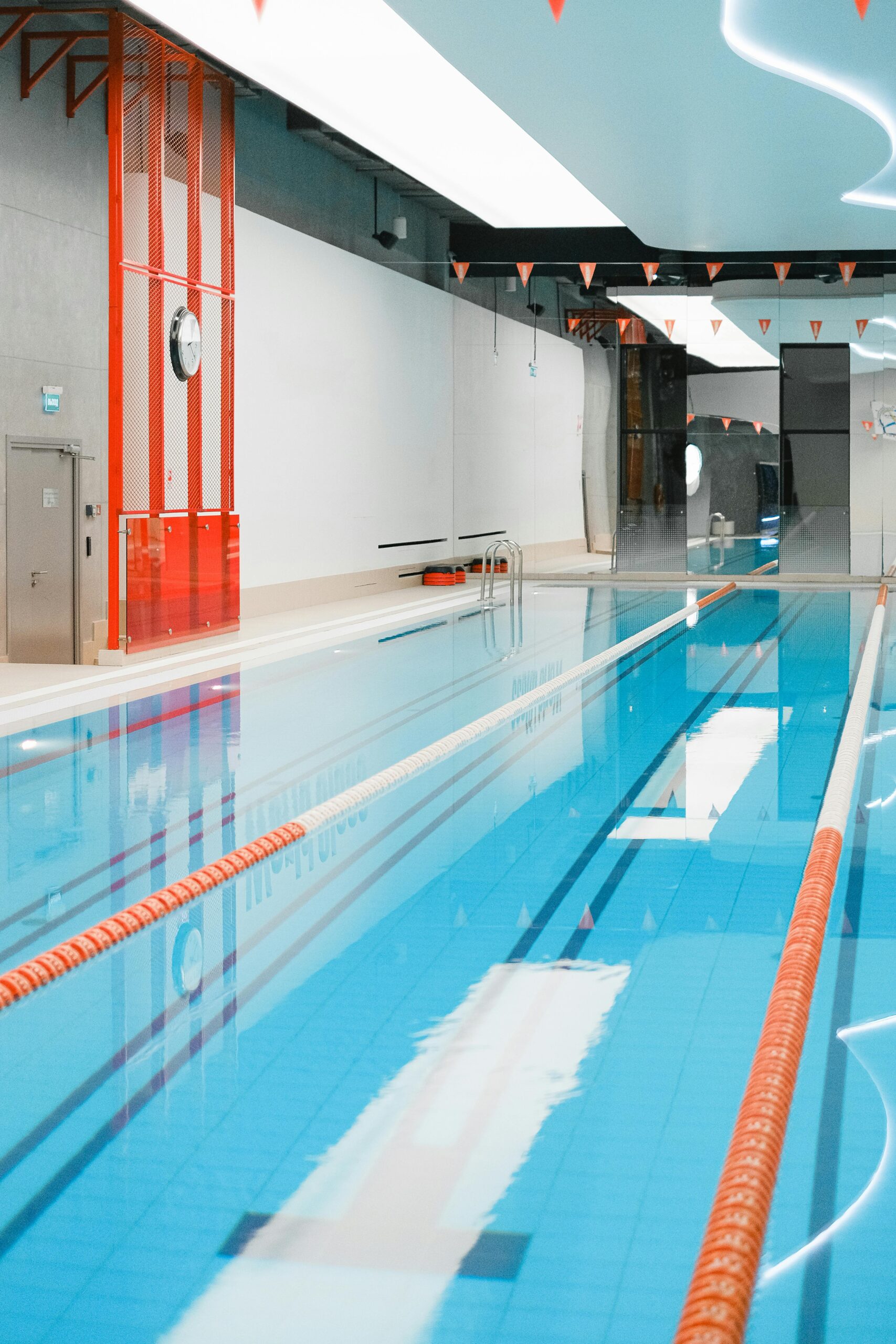 Bright indoor swimming pool with reflective ceiling and clear lanes ideal for swimming practice.